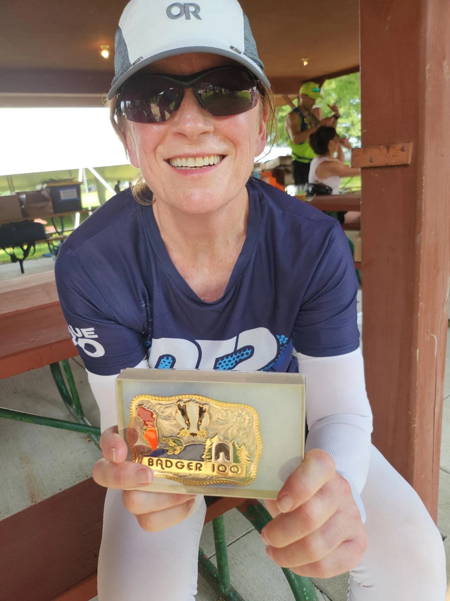 Julie Knight holding her 100-mile finisher's belt buckle, earned in 2025